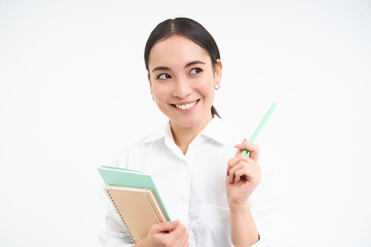 ノートとペンを持って微笑む女性