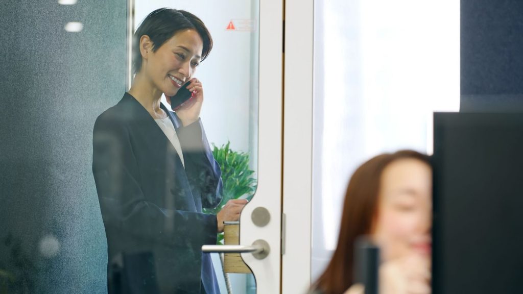 フォンブースで電話する女性